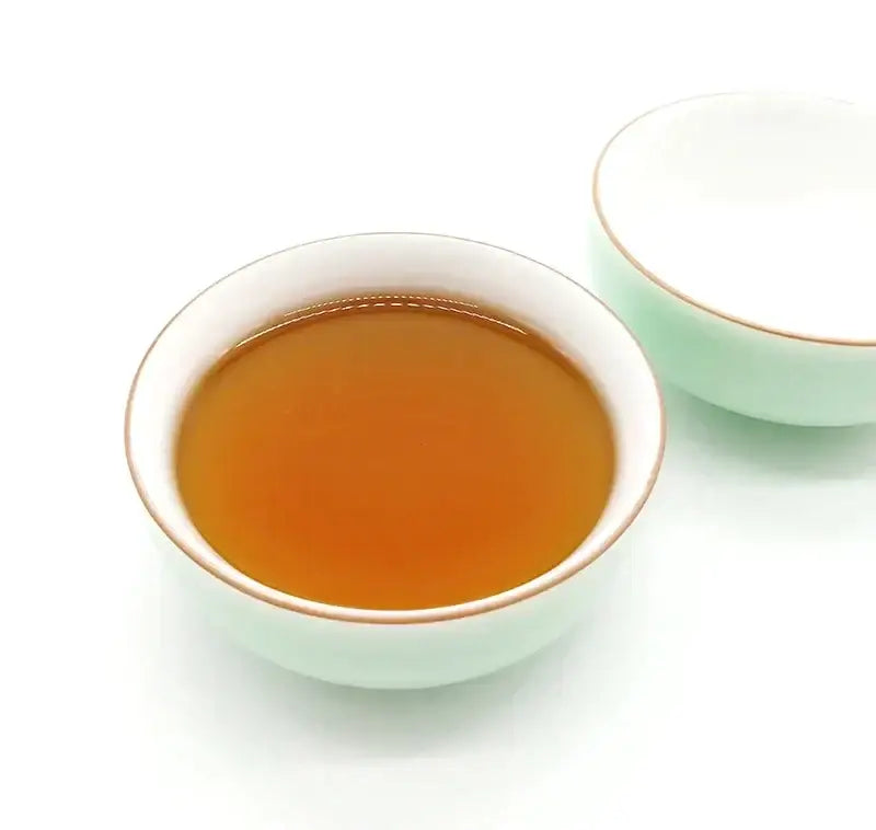 A delicate mint green celadon tea cup set with white porcelain and gold rim filled with rich amber tea by decorbites