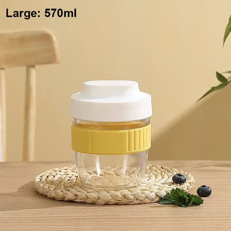 Clear glass travel mug with white lid and yellow silicone grip band in mint green and yellow decorbites breakfast cup
