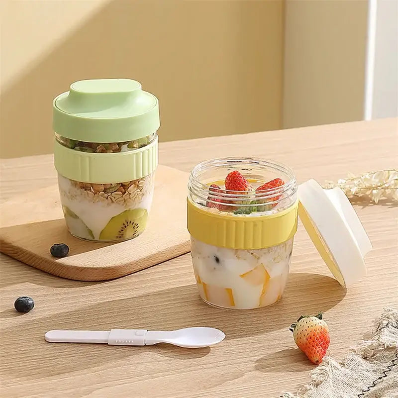 Two colorful translucent plastic decorbites breakfast cups in mint green and yellow with ribbed silicone lids filled with parfait