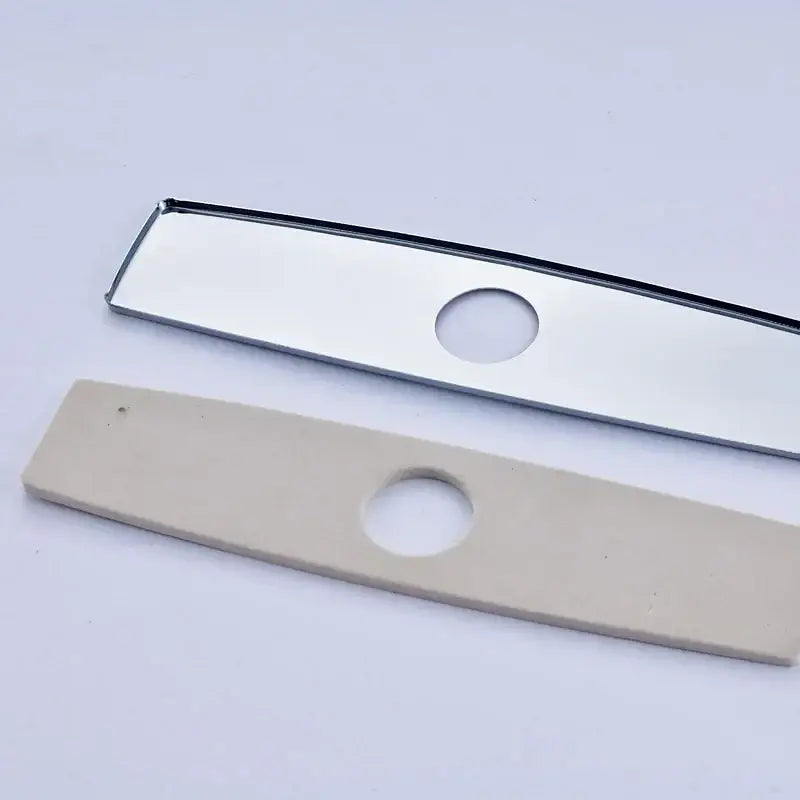 Two rectangular metal and beige plastic deck plate escutcheon inserts with central hole for kitchen and bathroom sinks