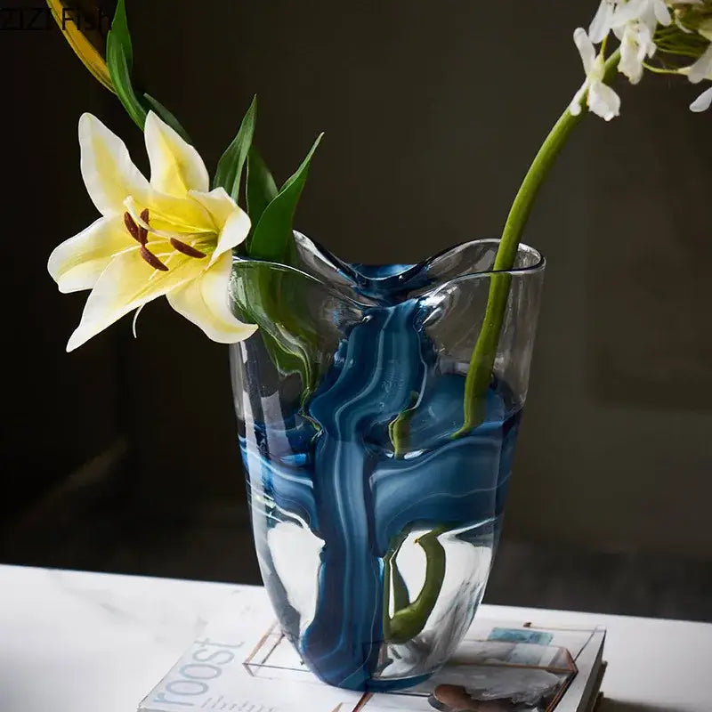 A modern abstract blue striped glass vase with swirling patterns holding a yellow lily for living room decorbites decor
