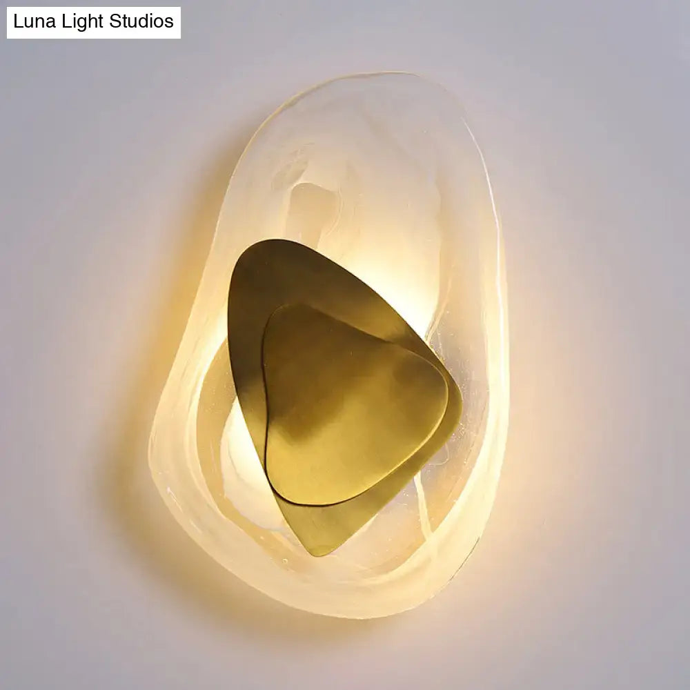 Modern abstract clear glass rock wall sconce with frosted glass and layered brass plates in black and gold direct wired electric design