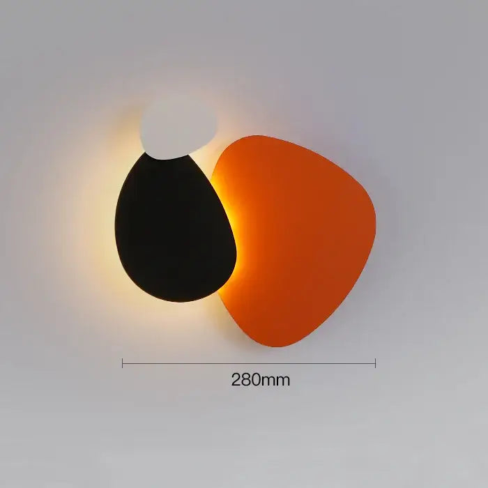 Modern abstract geometric art wall lamp with overlapping matte black and vibrant orange panels for bedroom and living room
