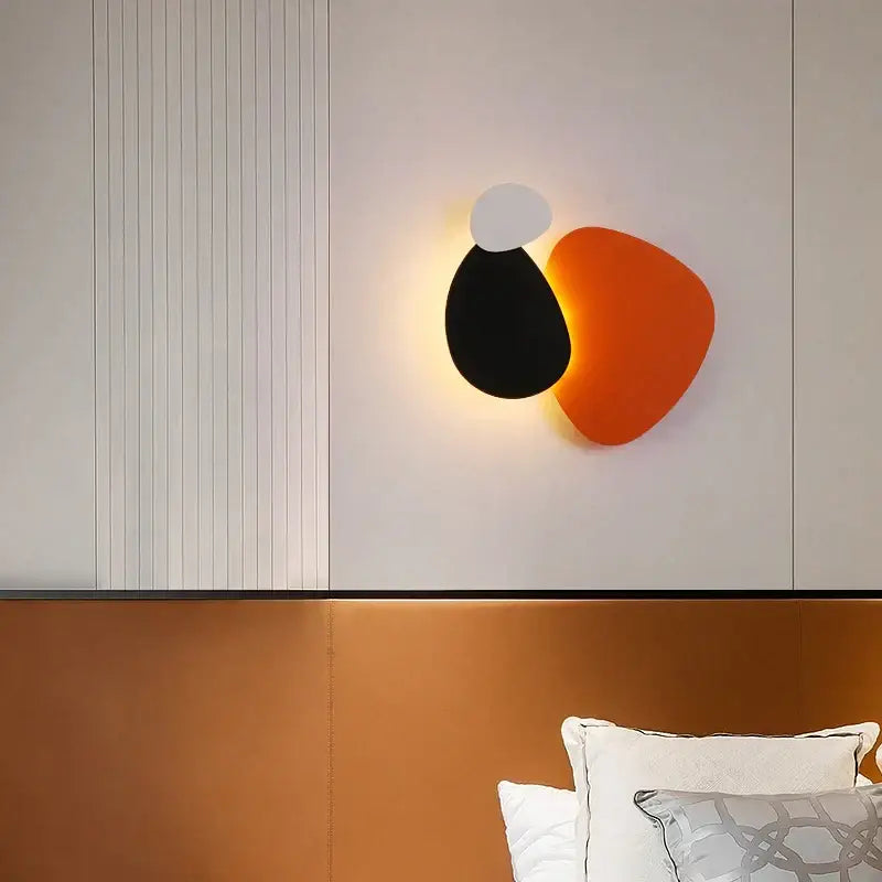 Modern abstract geometric art wall lamp with three overlapping matte black orange and white shapes for bedroom and living room
