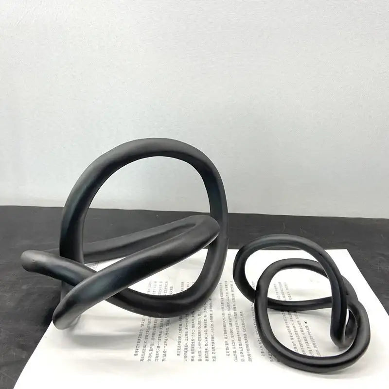 Black matte-finished modern abstract gold ring knot sculpture with smooth rounded loops for living room decor