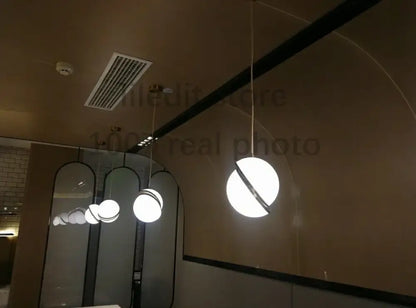Modern acrylic ball pendant lamp featuring a white spherical pendant light with a black circular accent band for living room