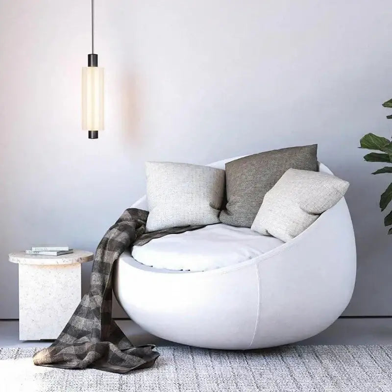 White upholstered egg-shaped armchair with soft cushions and plaid throw paired with decorbites acrylic minimalist pendant lights