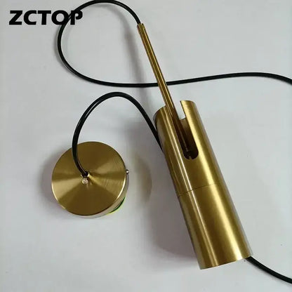 Gold-colored cylindrical pendant light with black cord finish options works beautifully in modern kitchen settings
