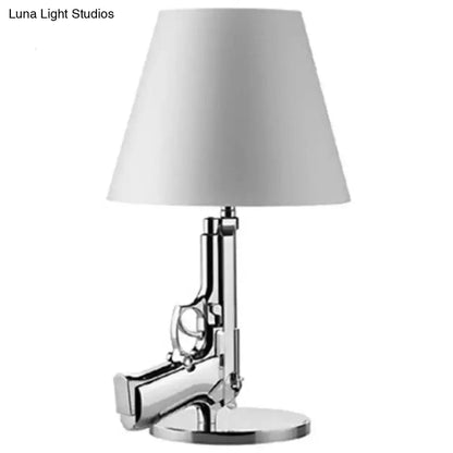 Modern ak47 gun lounge floor lamp with chrome finish pistol base and white conical shade in silvery gold lustre