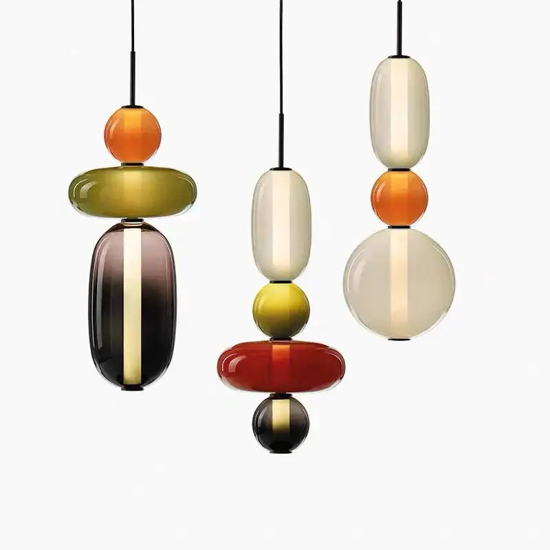 Three modern pendant lights with colorful glass ball orbs in amber cream red and olive green for dining room use
