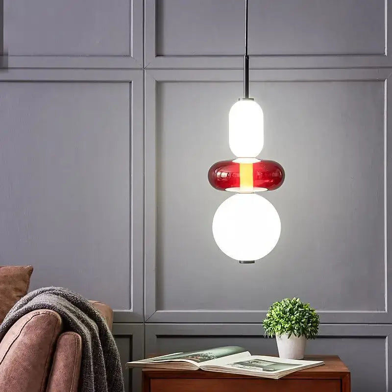 Modern pendant lights with stacked white and red colorful glass ball orbs and a sleek black hanging rod for dining rooms