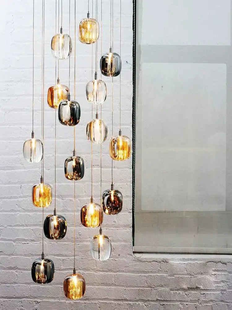 Modern amber and gold crystal led ceiling chandelier featuring hanging glass orbs in clear, amber, and dark metallic finishes
