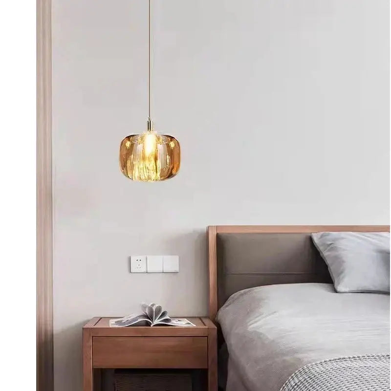 A modern amber and gold decorbites crystal led chandelier pendant light with textured ribbed glass hangs above a wooden nightstand