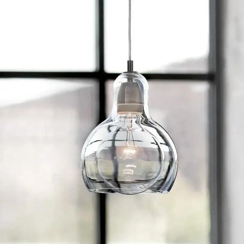 Modern amber and gray glass pendant lights featuring a clear bulbous glass pendant with vintage filament for dining room use
