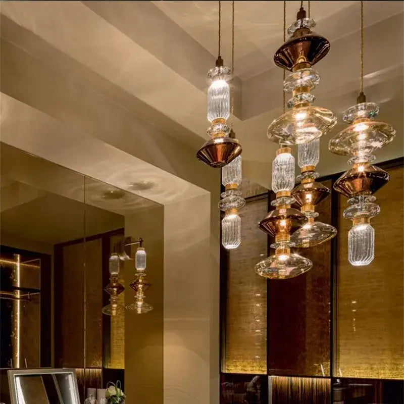 Elegant modern amber and brown glass ballet pendant lamp with brass and faceted crystal accents for dining room lighting