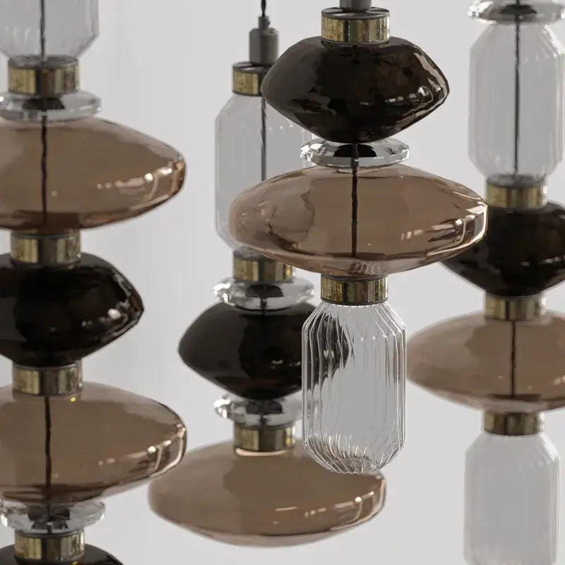 A modern ballet pendant lamp with stacked amber and brown glass orbs and gold accents for dining room lighting