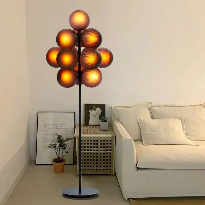 A modern amber bubble glass floor and table lamp set with a black metal stand and glowing amber glass spheres