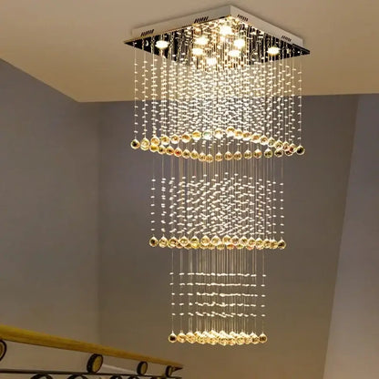 A modern amber and clear decorbites crystal teardrop stairwell chandelier with cascading beads and warm led lights