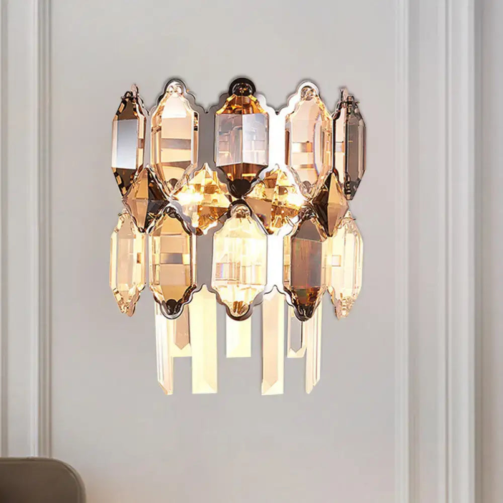 A modern amber and clear crystal wall sconce with cascading prisms and polished brass finish for staircase lighting
