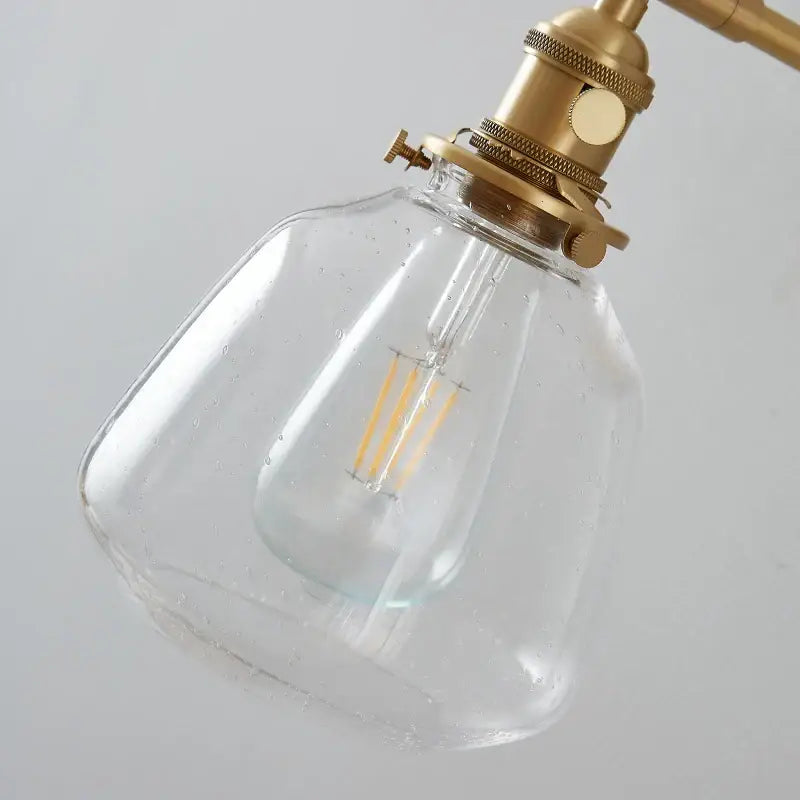 Modern amber clear glass wall sconce featuring a brass fixture and exposed filament bulb by decorbites clear glass