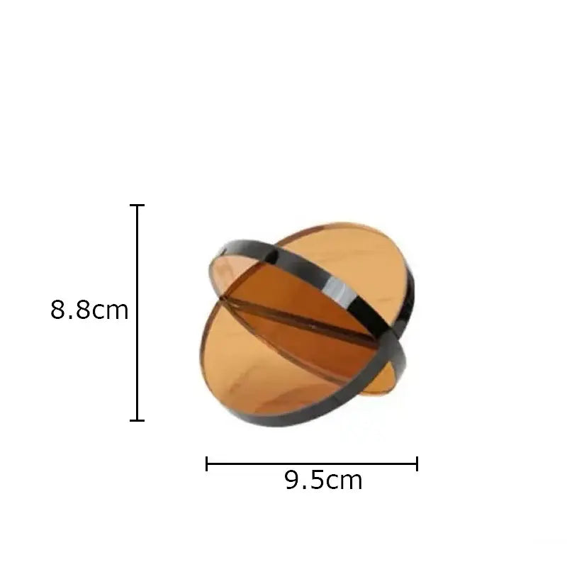 A sleek amber acrylic orb with a glossy black band as modern amber geometric cross ornaments bookends