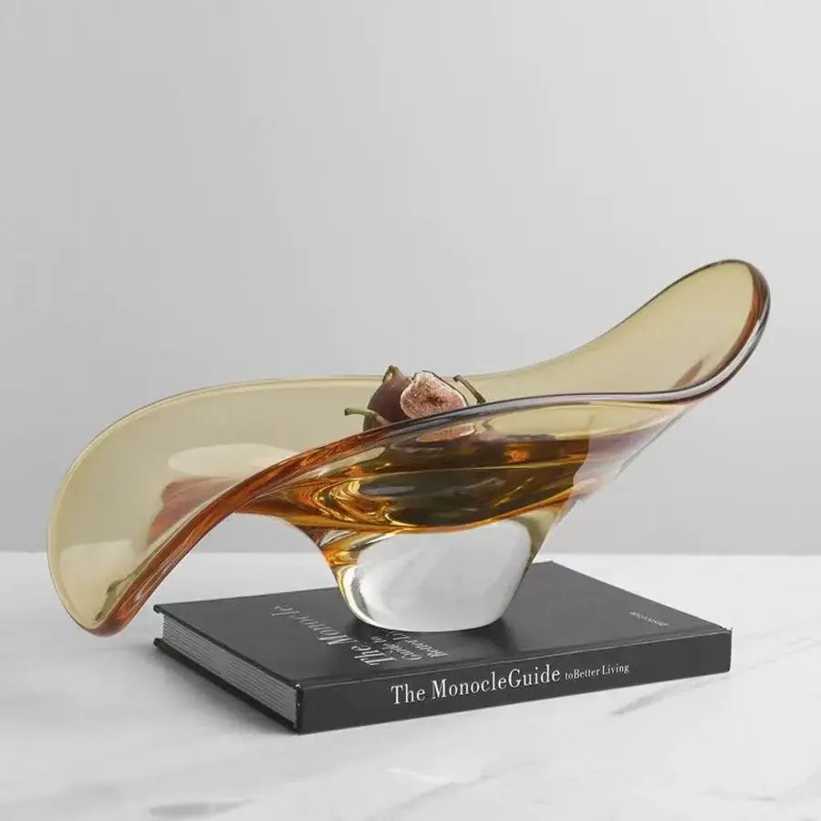 A modern amber geometric glass bowl tray with a sleek flowing design and a clear crystal base for decorbites decor