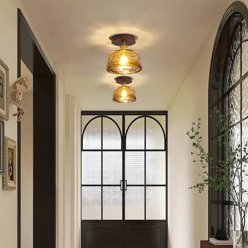 Two warm-toned amber glass and brass led ceiling lamps hang in a modern dining room ceiling lamp setting