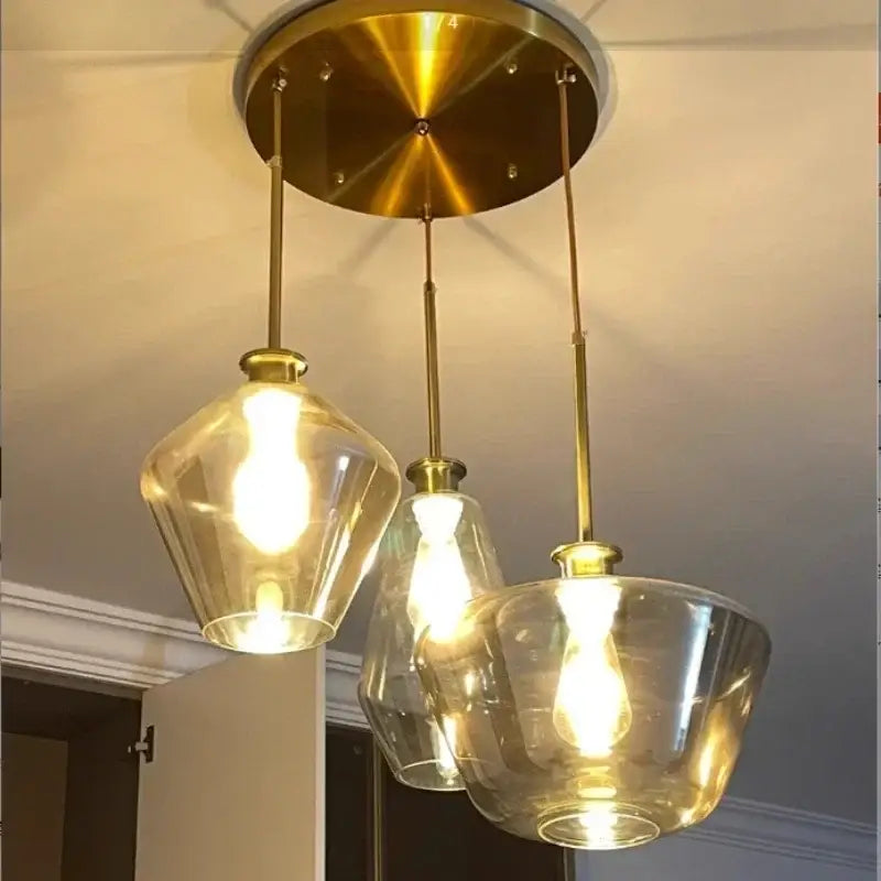Modern amber glass chandelier pendant light with brass finish and three clear glass shades for living room or dining room