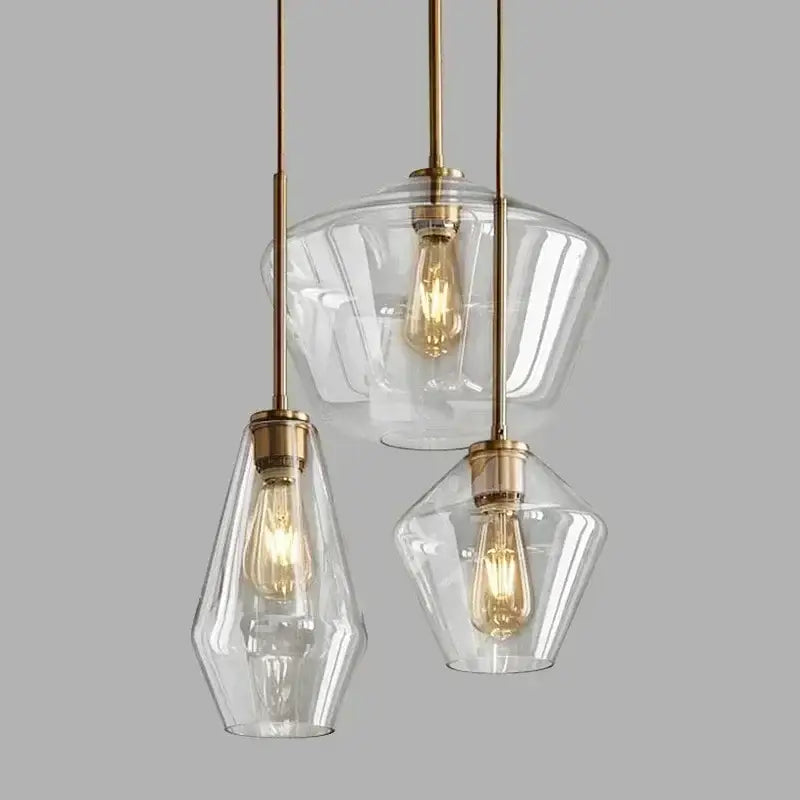 Set of three clear glass pendant lights with brass accents and exposed filament bulbs for living room chandelier