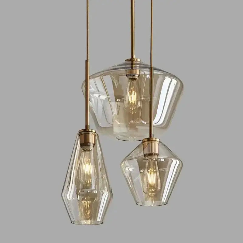 Set of three modern amber glass chandelier pendant lights with clear shades and brass fixtures for living room decor