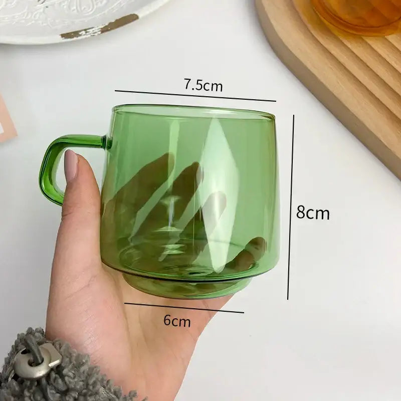 Modern amber glass coffee mug with black rim held in hand featuring translucent green decorbites glass coffee design