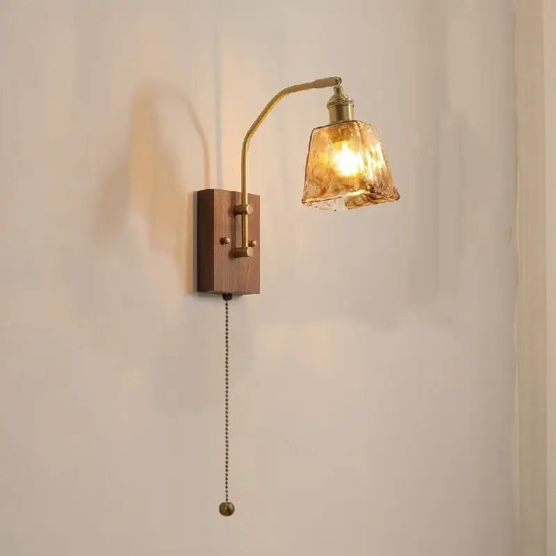 A warm-toned brass and wood wall lamp with adjustable arm and textured amber glass copper led shade for bedroom lighting
