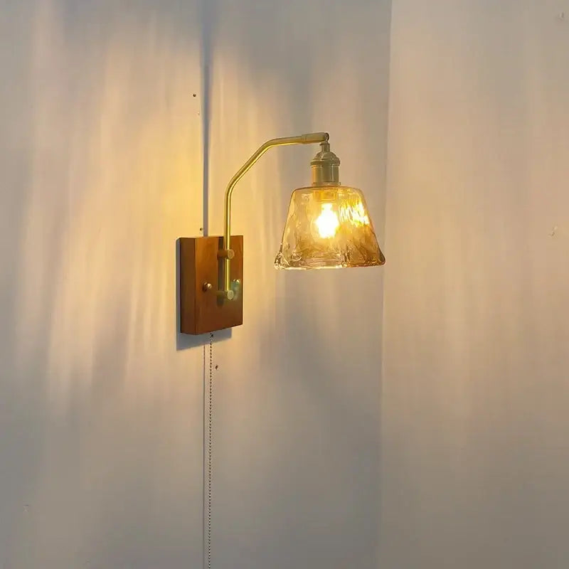 A warm-toned brass wall lamp with textured amber glass copper led shade and wooden mounting plate for bedroom lighting