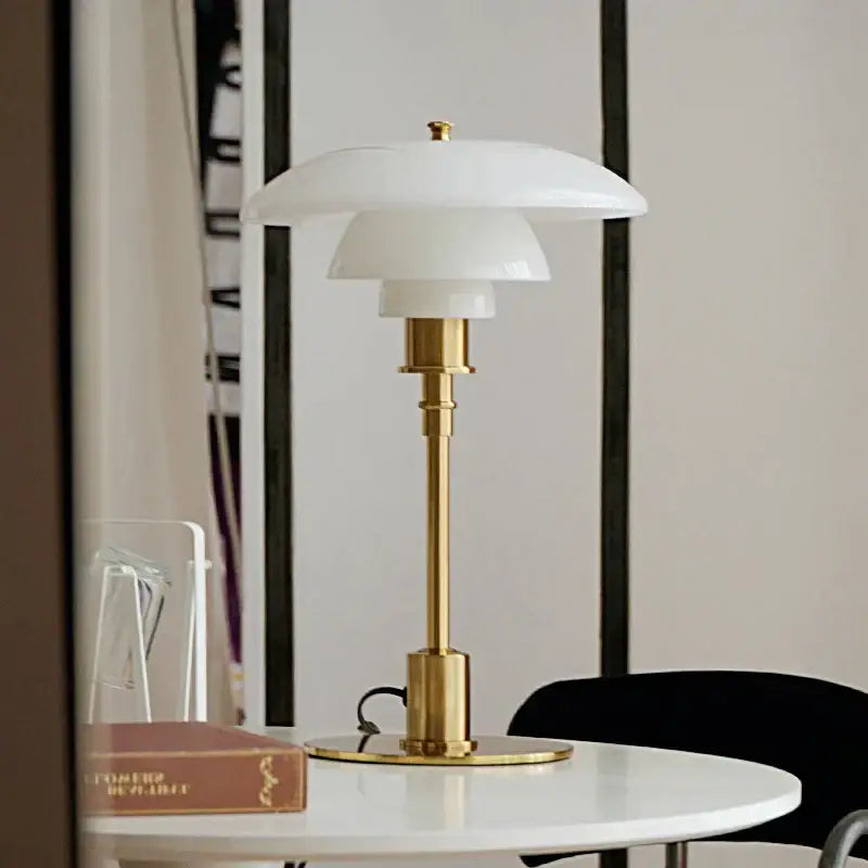 A sleek modern glass desk lamp with layered white shade and polished brass base perfect for home office decorbites desk lamp