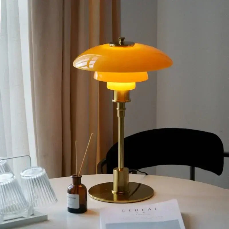 Modern amber glass desk lamp with warm yellow-orange translucent glass and golden brass finish for living room decorbites glass desk