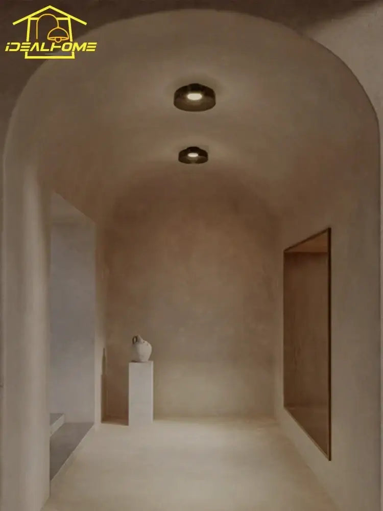 A minimalist white ceramic vase with textured surface next to a modern amber glass led ceiling light for living room