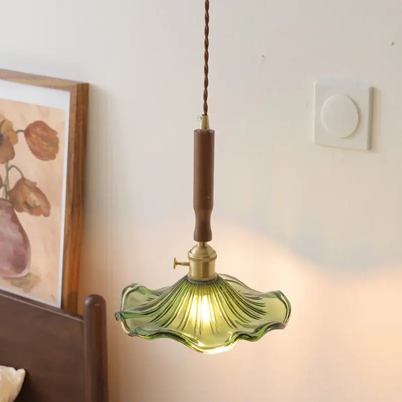 Modern pendant light with green decorbites amber glass, brass fixture, and wooden stem for dining room use