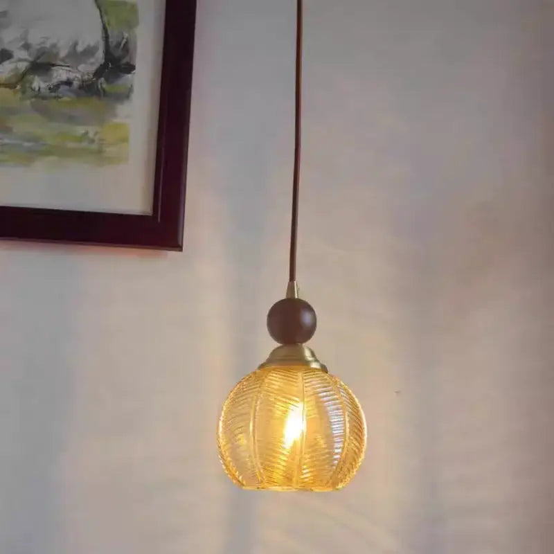 Modern amber glass led pendant light with textured ribbed design and dark wooden accent for dining room lighting