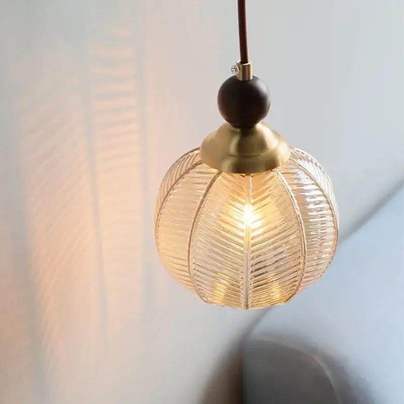 Modern amber glass led pendant light with textured leaf-like ridges and brass accents for dining room lighting