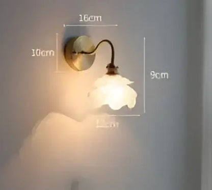 A delicate vintage-style led wall lamp with a brass arm and white ceramic flower shade for bedroom wall sconce