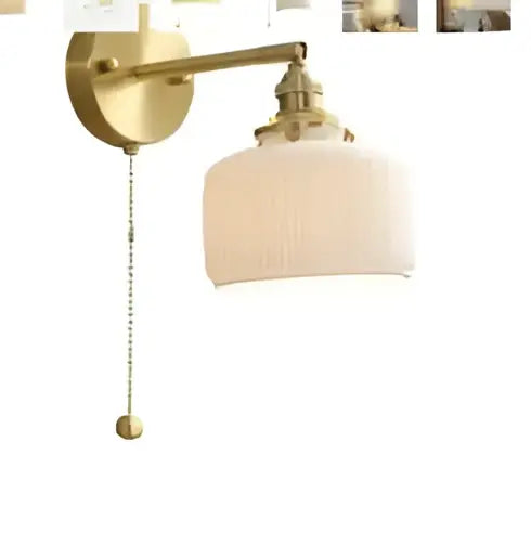Brass-finished wall lamp with pleated off-white fabric shade and pull chain featuring modern amber glass led wall design