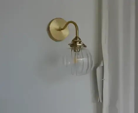 Modern amber glass led wall lamp with gold-toned brass sconce and clear glass globe for bedroom lighting
