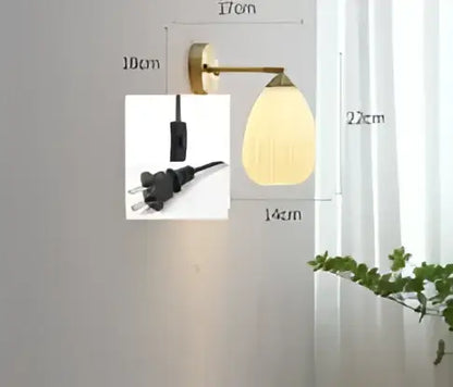 Modern amber glass led wall lamp with warm yellowish-gold brass sconce and frosted oval shade for bedroom use