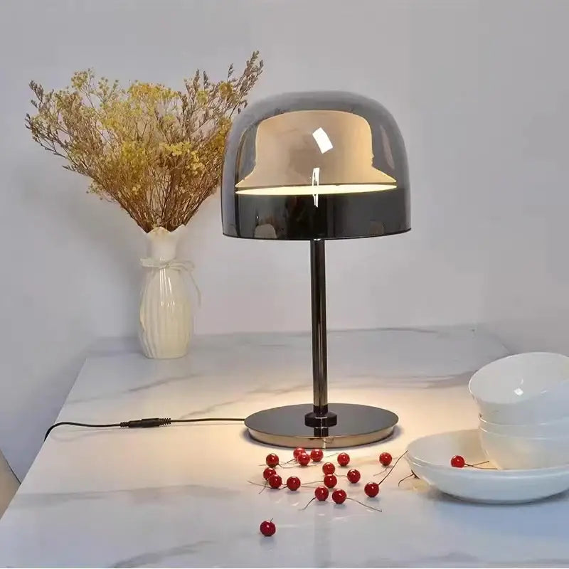 Modern chrome-finished table lamp with sleek dome shade and cylindrical base paired with amber glass pendant light copper finish