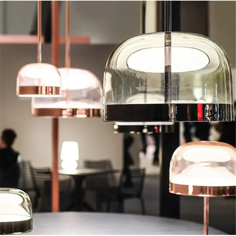 Modern amber glass pendant light with dome-shaped clear glass, copper accents, and black base for dining room lighting