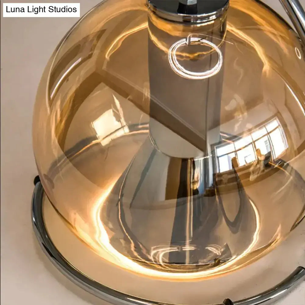 A modern amber glass pendant light with a sleek amber-tinted dome and polished chrome base for kitchen use