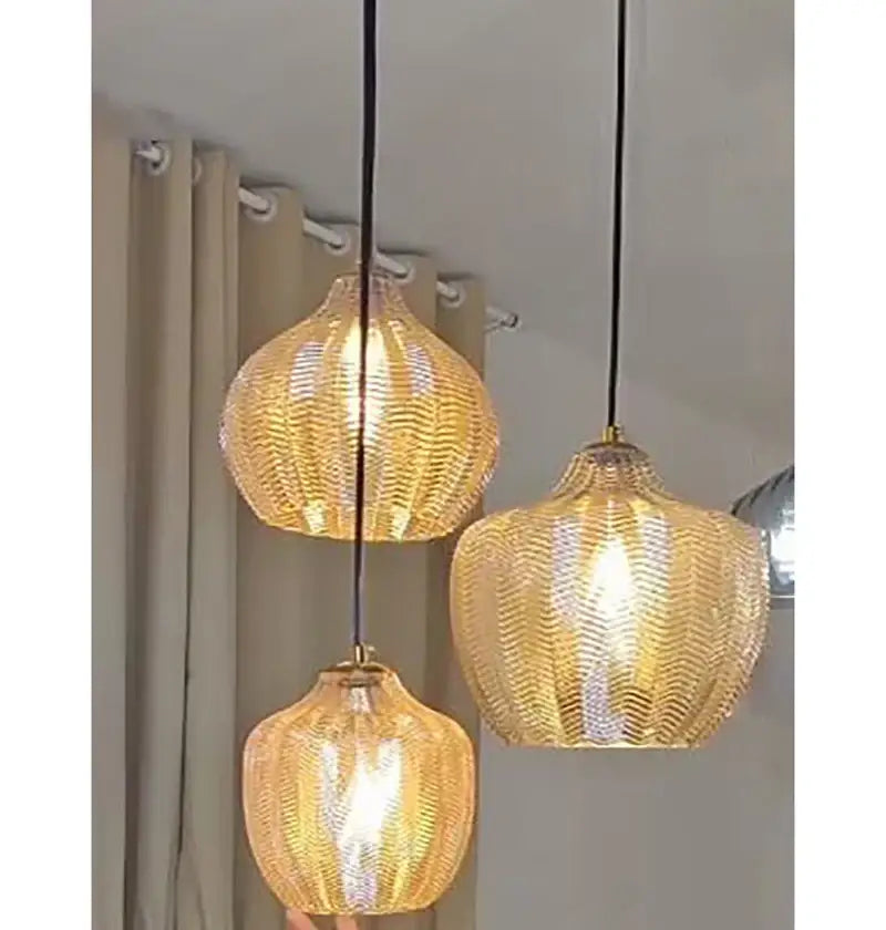 Three warm-toned amber gray glass pendant lights with wavy textured design hang from black cords for dining room decorbites amber gray