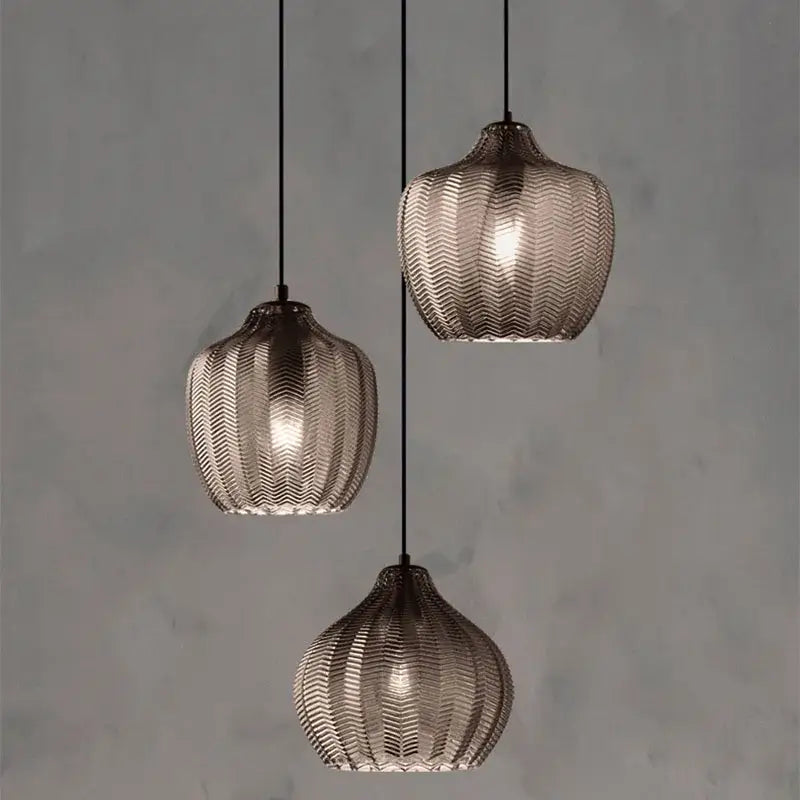 Three amber gray glass pendant lights with woven mesh design and warm glow for modern dining room decorbites amber gray