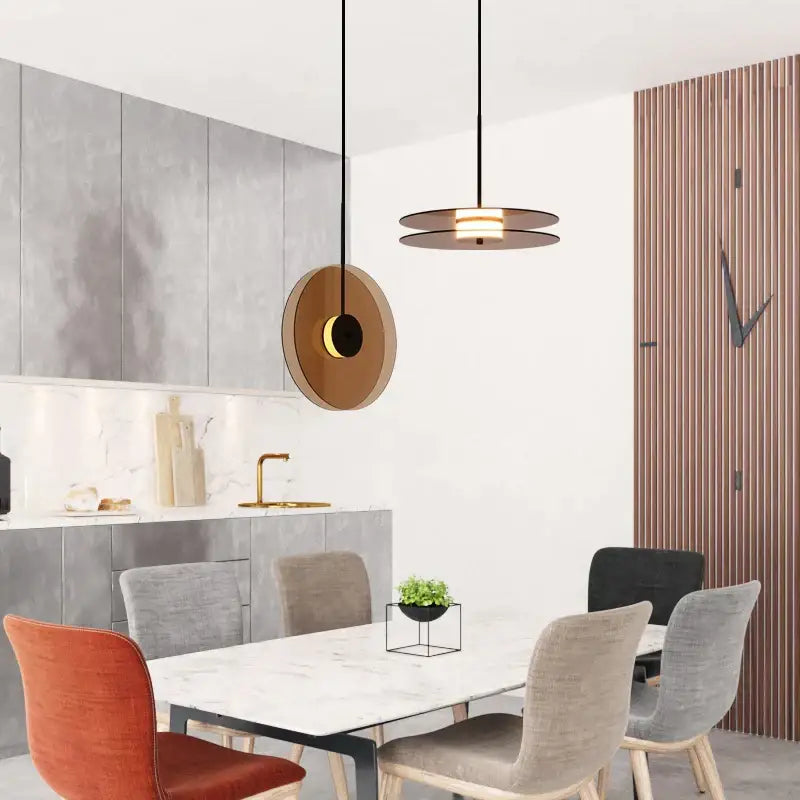 Modern circular pendant light with warm brass finish and black accents featuring decorbites amber smoke gray glass