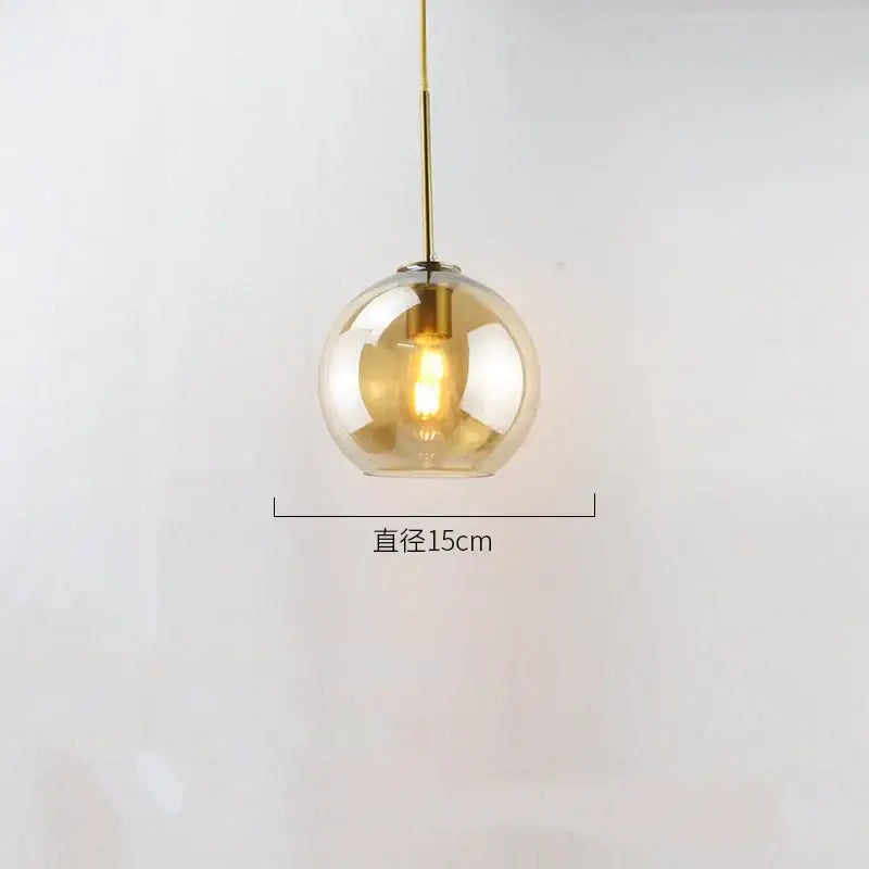 A sleek 15cm amber glass ball led pendant light with a polished brass stem for modern dining room decorbites pendant lights